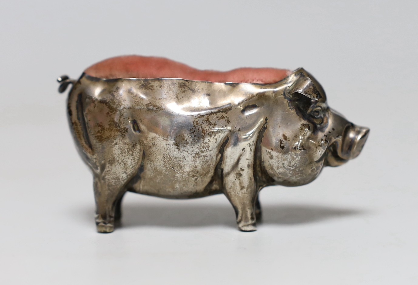 A George V silver mounted pig pin cushion, H?, Birmingham, 1912, length 77mm.